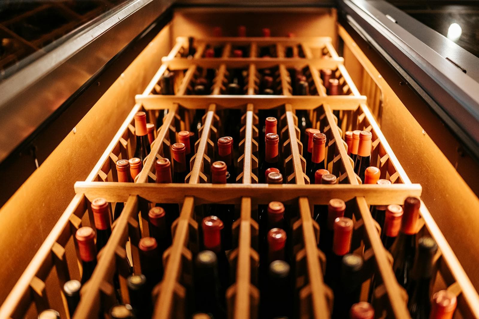 Designer wine cellar with illuminated diagonal racking and bottles arranged on backlit wooden shelves