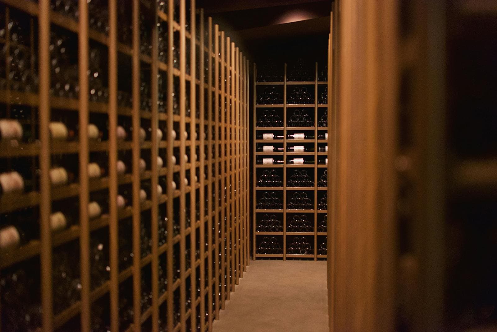 Custom-built wine cellar with floor-to-ceiling wood racking holding hundreds of bottles in soft warm lighting